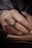 A hand with a decorative ring is holding a black fountain pen, poised over a small hardcover book, suggesting the act of writing or taking notes.