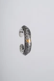 Close-up of a delicate silver ring with an intricate wave pattern inspired by the sea.