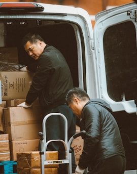 two men loading boxes into the back of a van