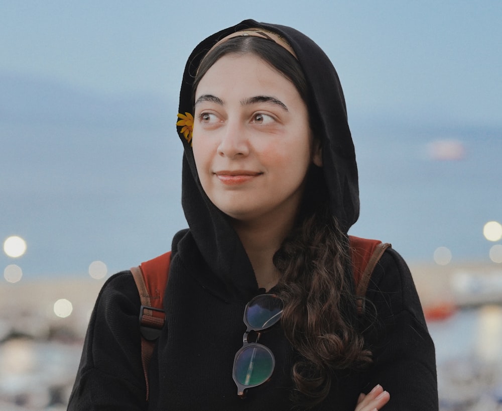 a woman wearing a black hoodie and sunglasses