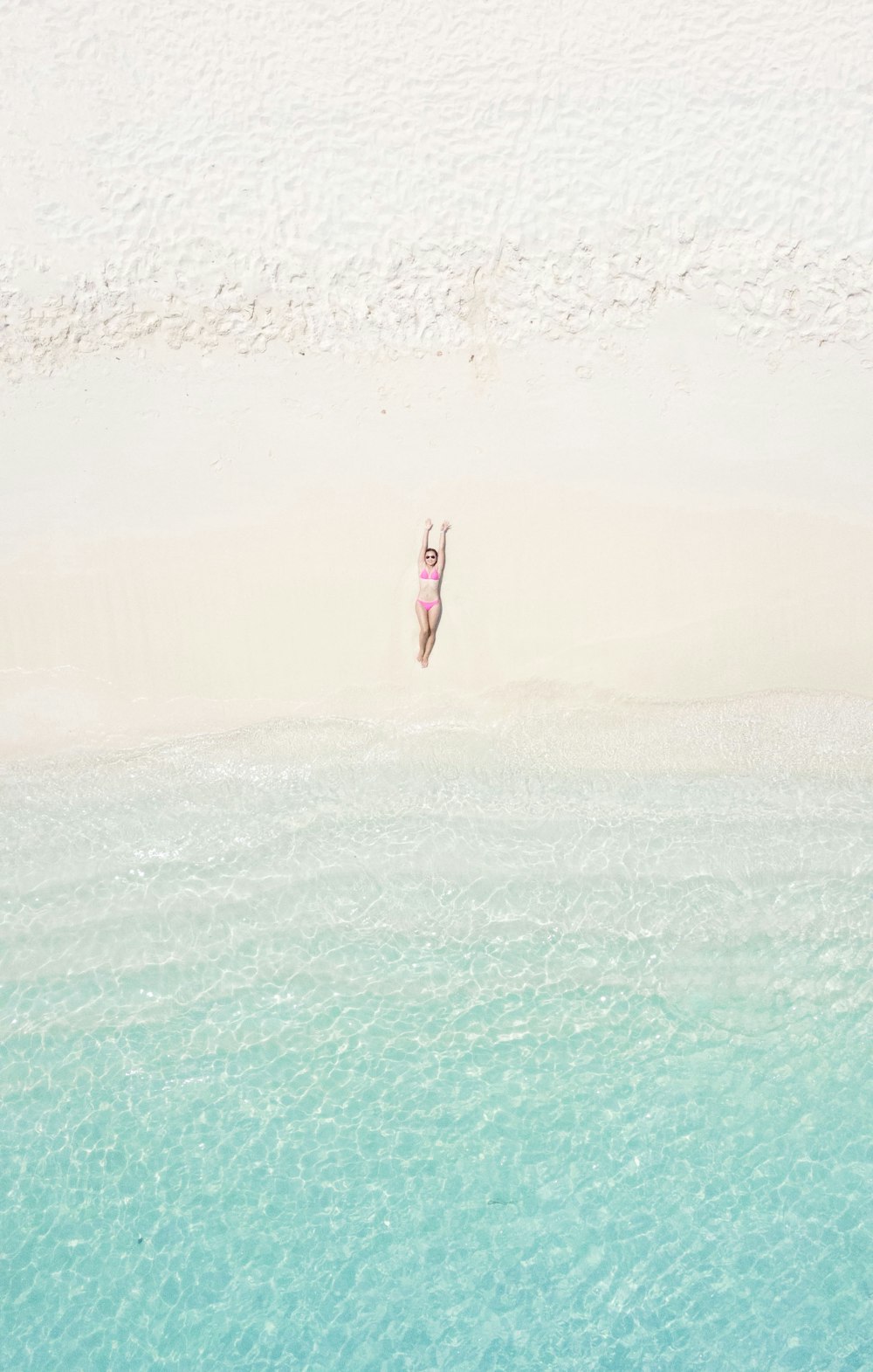 a woman in a pink bikini standing on a beach