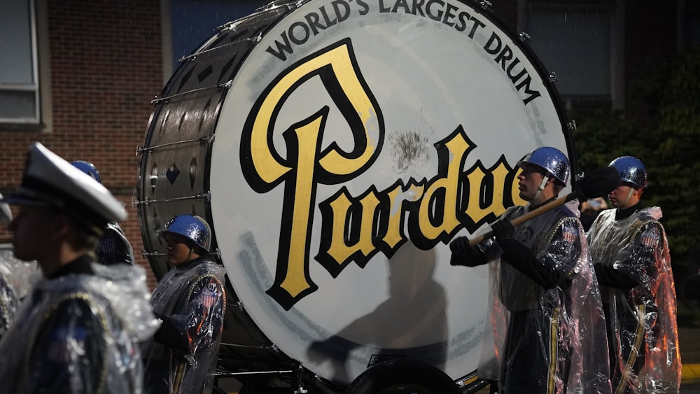 a group of men standing next to a large drum