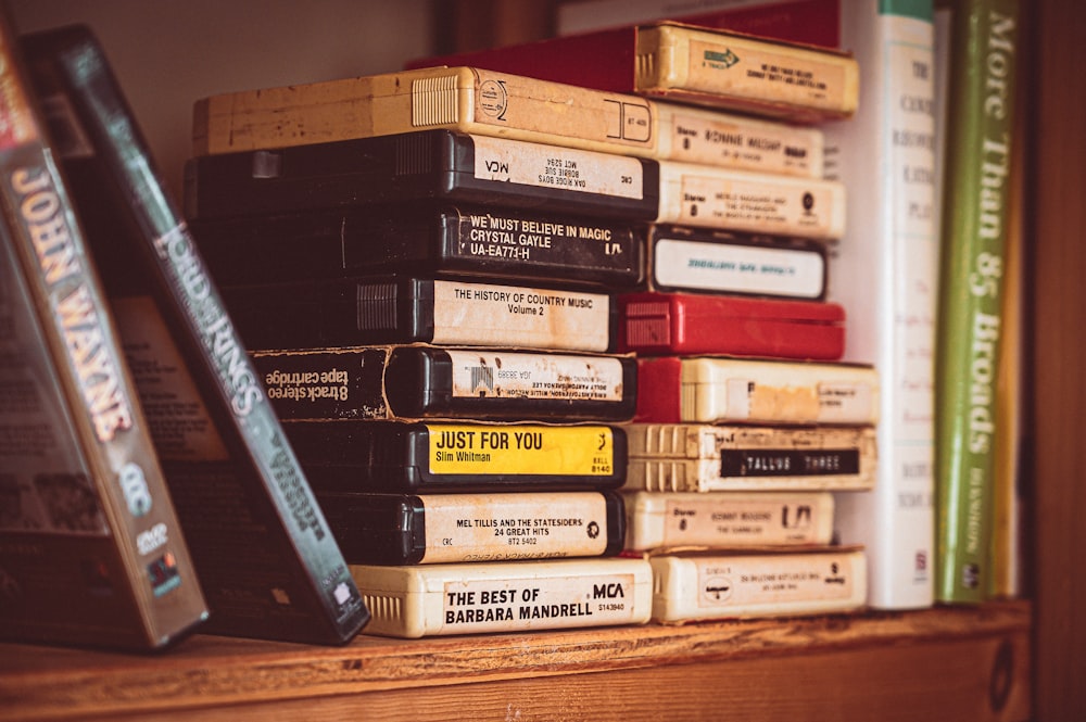 a stack of books sitting on top of a wooden shelf