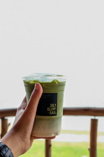 A friendly barista handing over a sealed PET can smoothie at a busy Istanbul metro station pickup point.