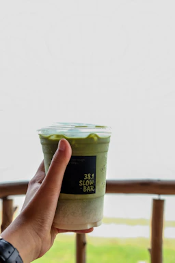 A friendly barista handing over a sealed PET can smoothie at a busy Istanbul metro station pickup point.