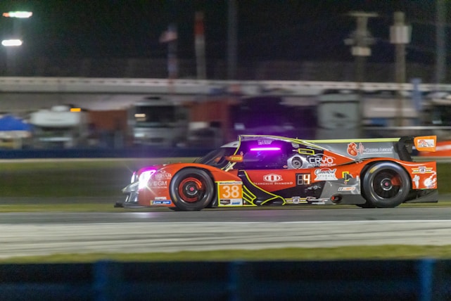 A sleek racing car showcasing a vibrant custom livery under bright track lights.