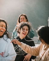 A group of people are laughing and enjoying a moment outdoors with a bright, gentle light illuminating the scene.