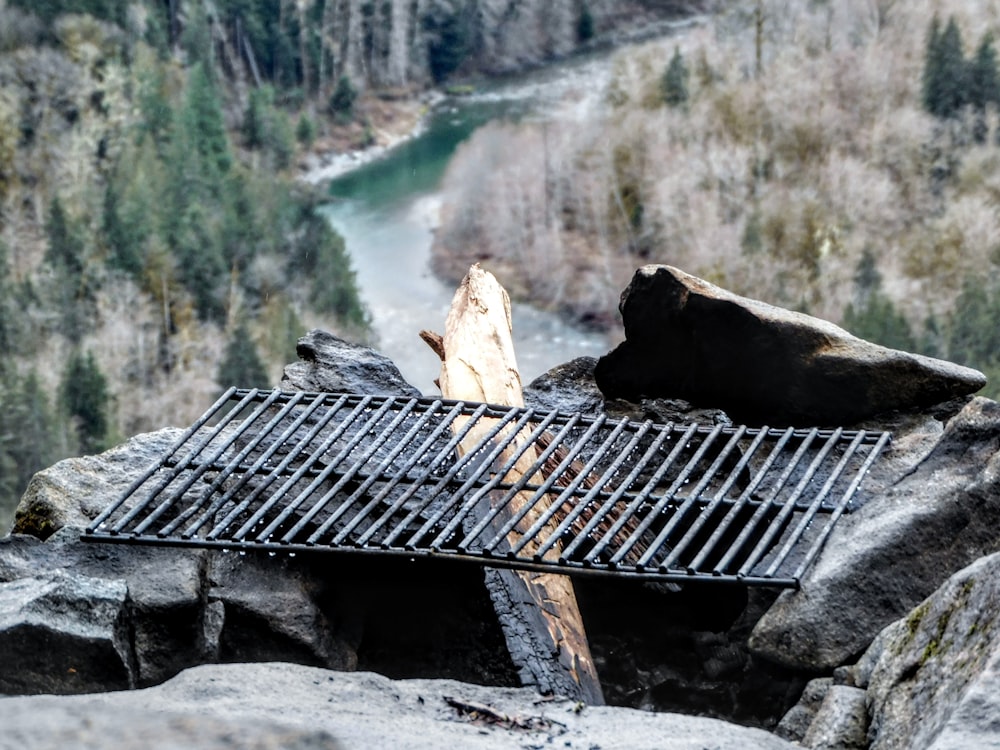 a grill on a rock with a river in the background