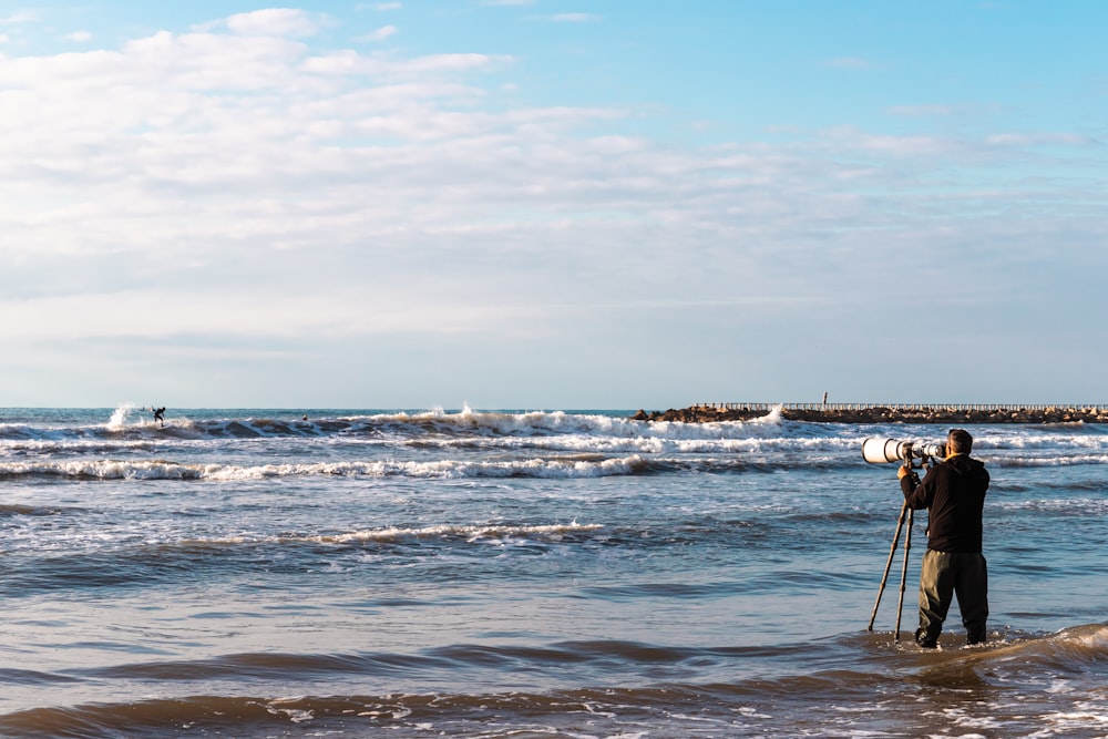 a man standing in the ocean holding a camera