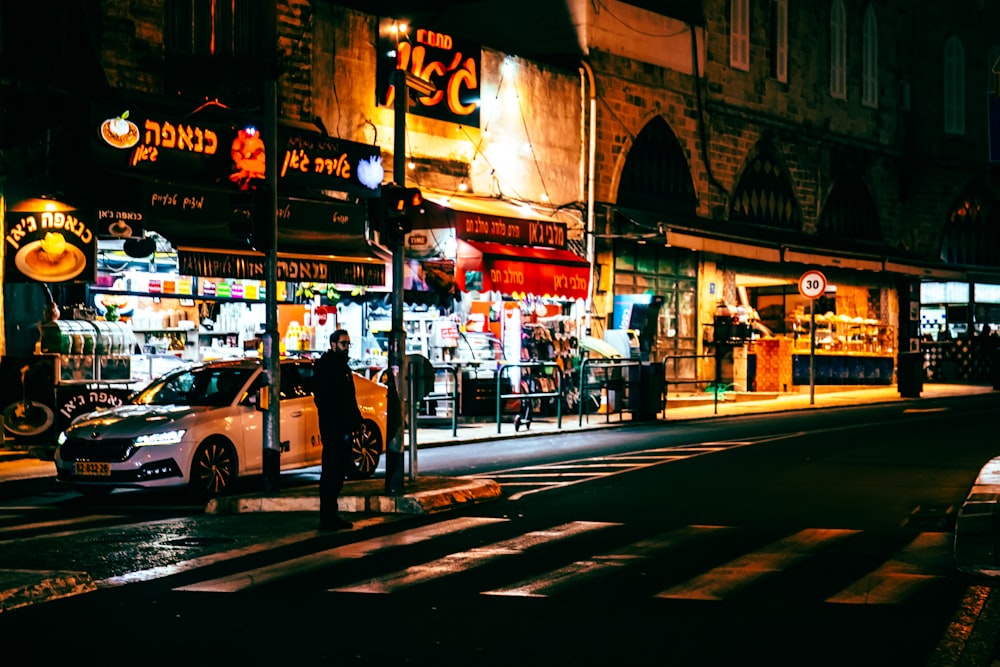 a city street at night with a car parked on the side of the road