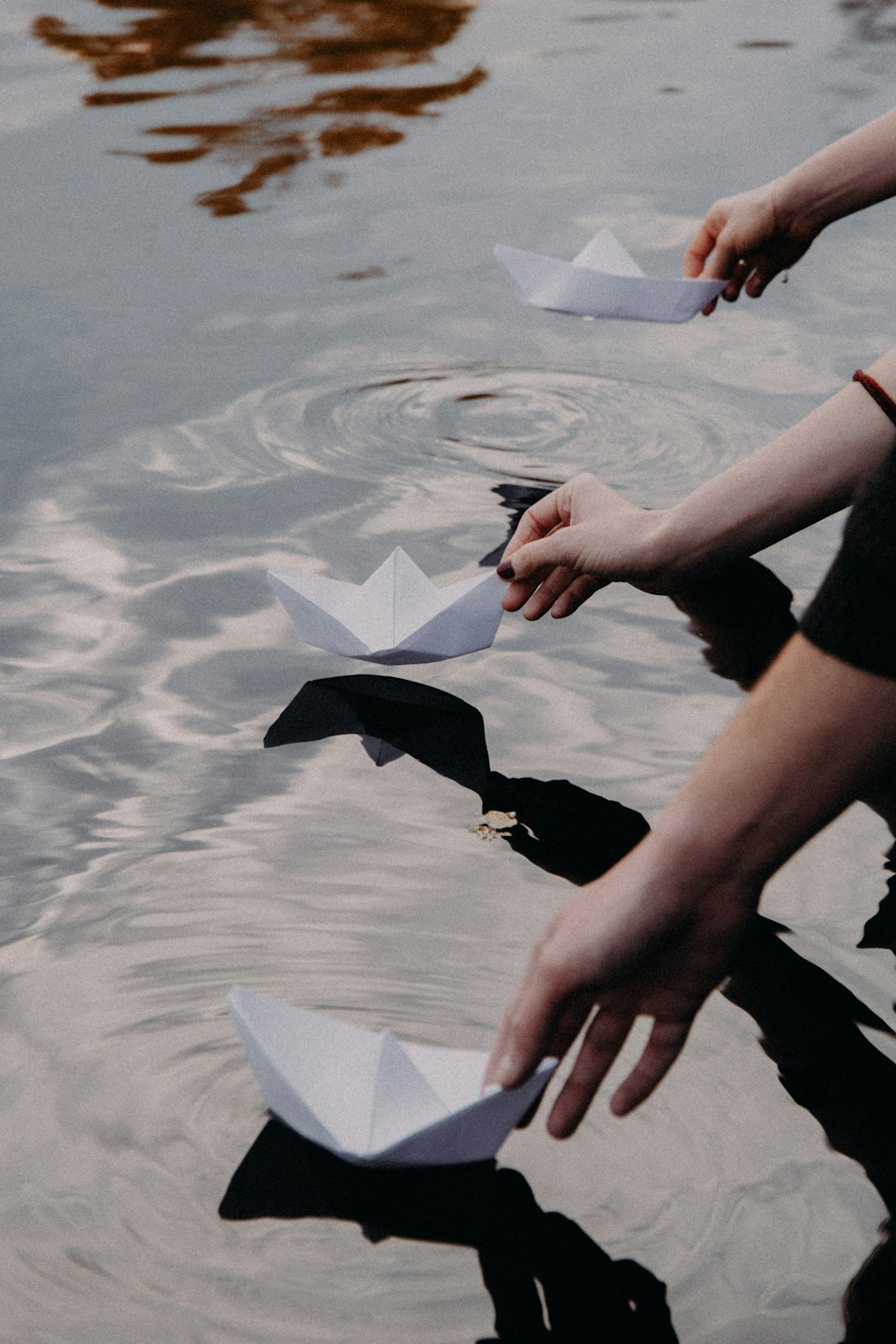 a group of people holding paper boats in the water