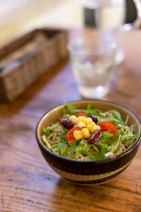 A colorful bowl of fresh, protein-rich salad with vegetables and grains on a wooden table.