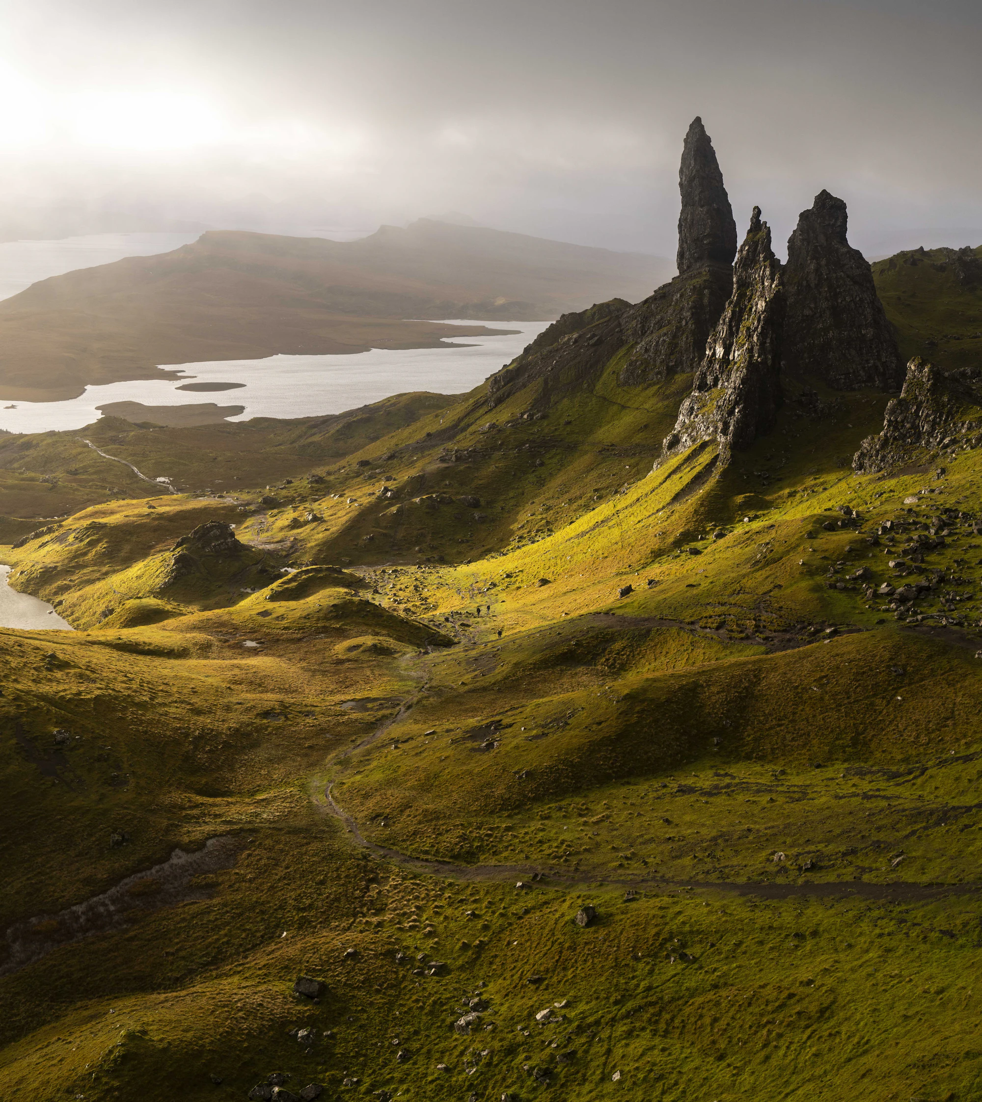A large grassy hill and loch at sunrise, warm pink and orange light