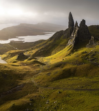 landscape photography,how to photograph the old man of storr on skye; a large grassy hill with a lake in the middle of it