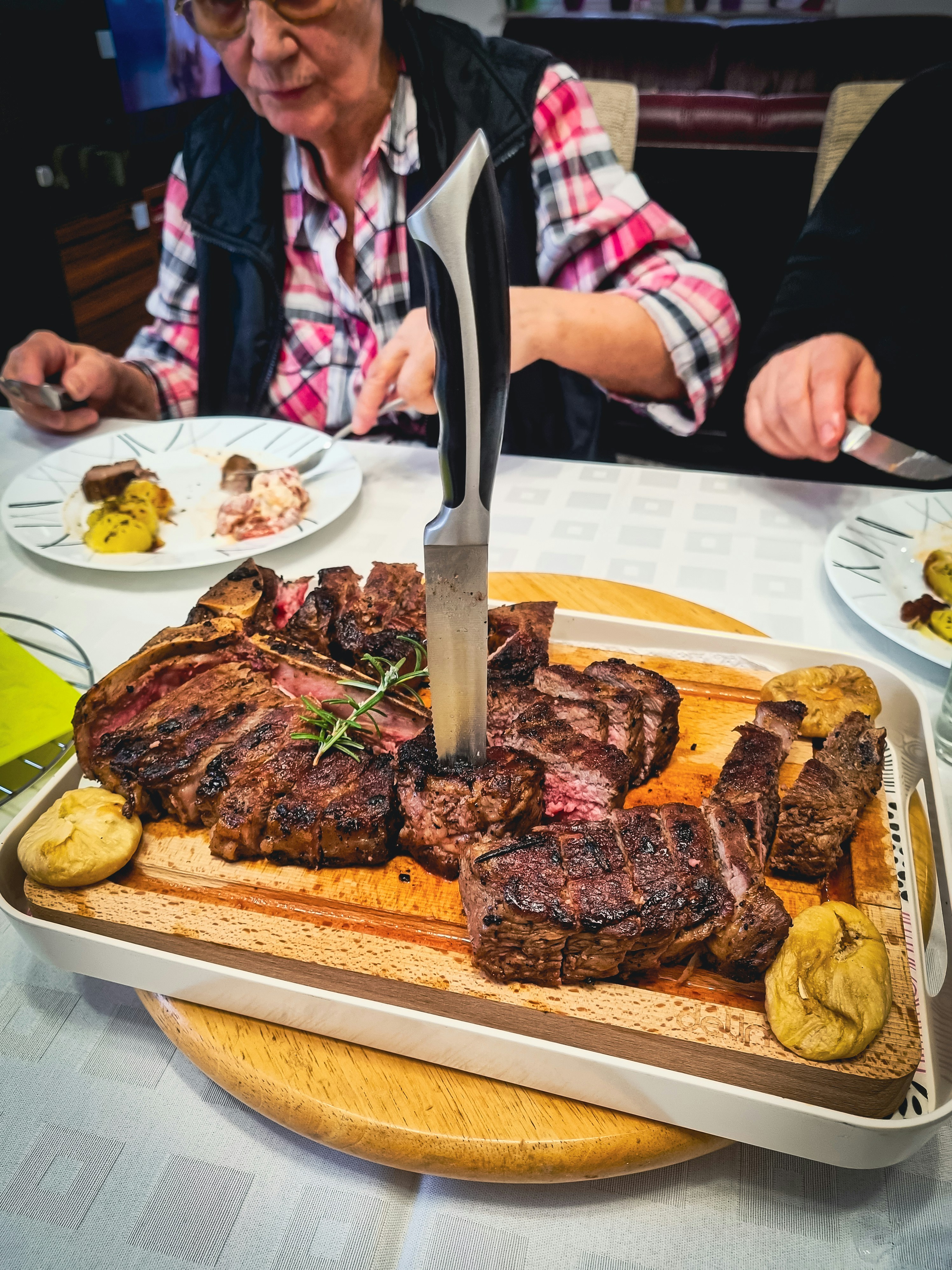 Large T-bone steak grilled to perfection with rosemary and potatoes on a wooden board
