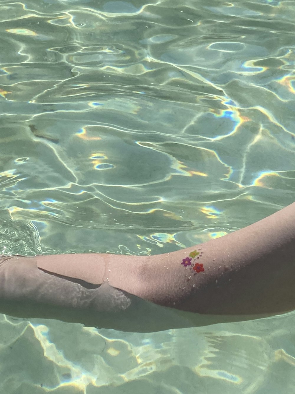 a person's arm in the water with a flower on it