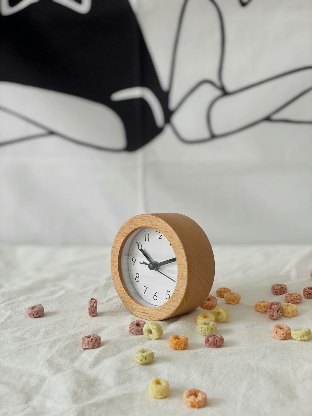 a wooden clock sitting on top of a bed covered in cereal