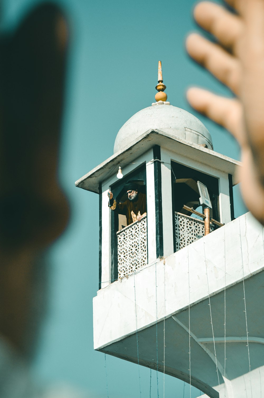 a person holding their hand up to a bell tower