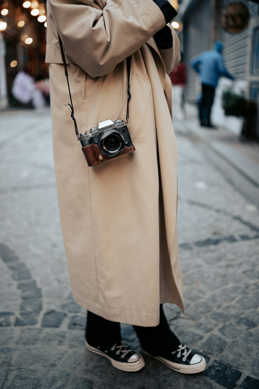 a woman in a trench coat holding a camera