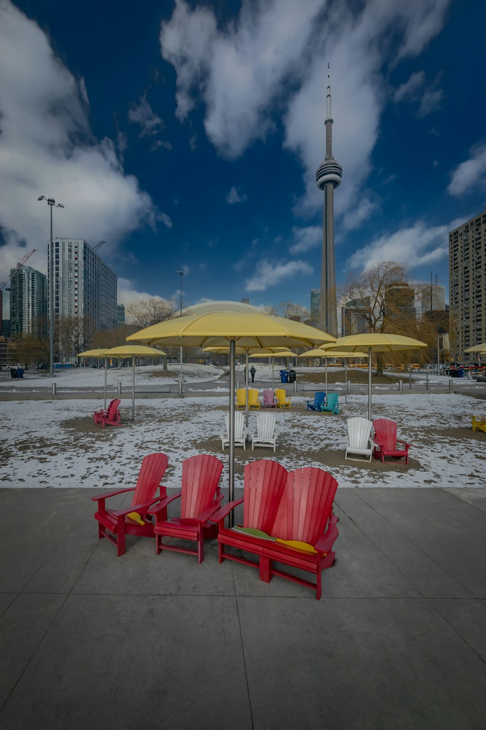 a couple of red chairs sitting under a yellow umbrella