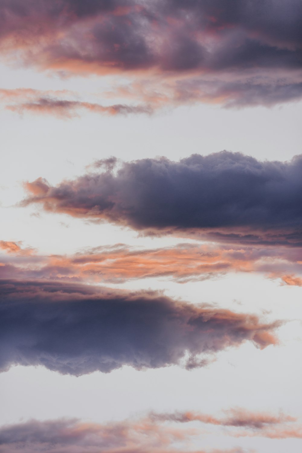 a plane flying through a cloudy sky at sunset