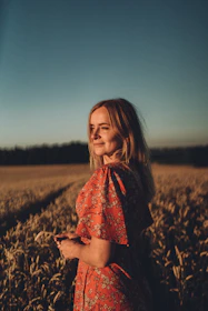 a woman in a red dress standing in a field