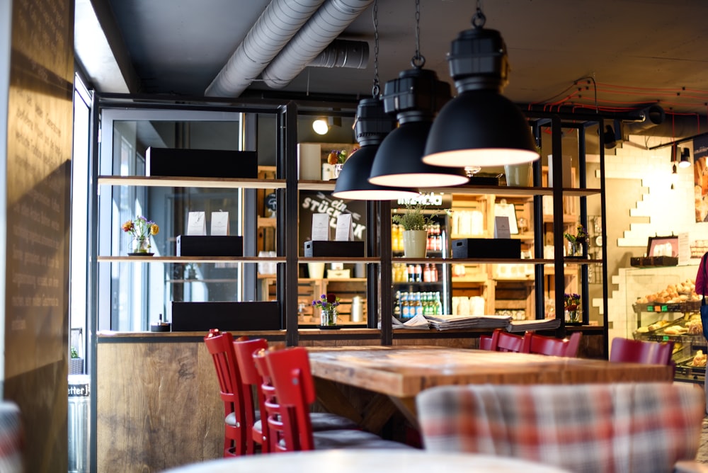 a restaurant with a large wooden table surrounded by red chairs