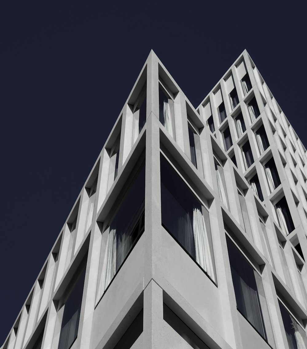 a tall white building with windows and a sky background