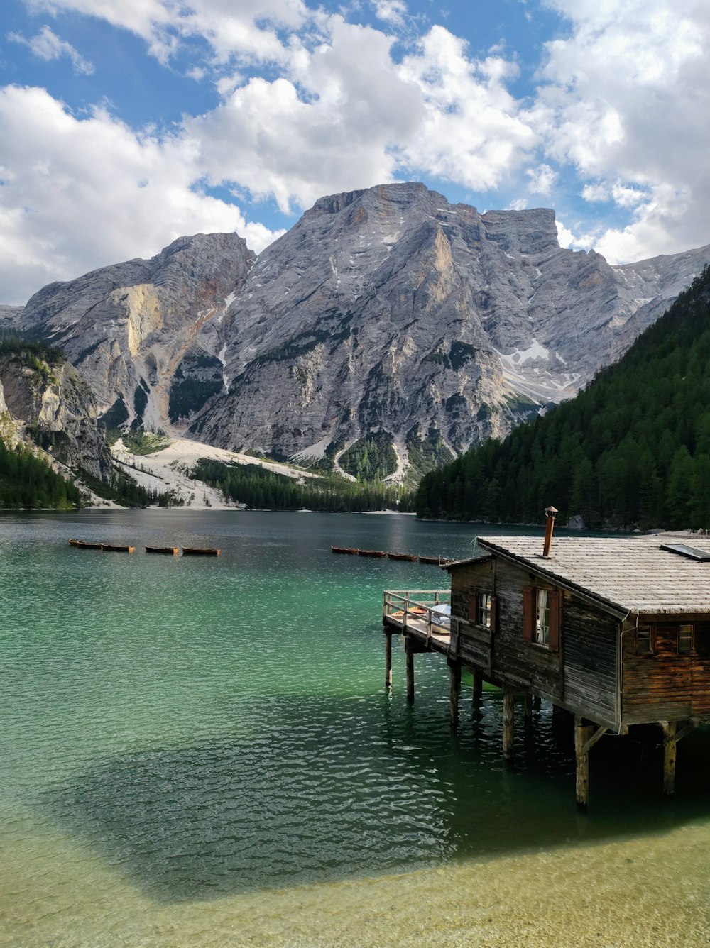 a wooden dock sitting on top of a lake next to a mountain