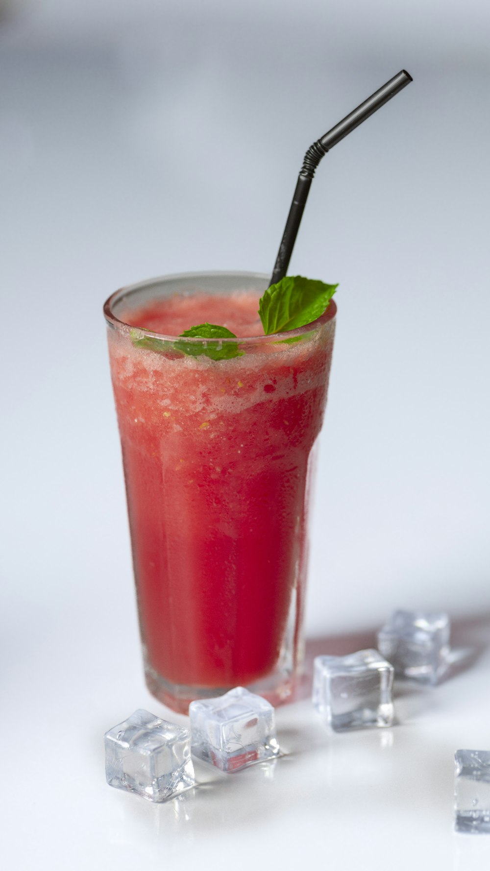 a glass of watermelon and ice cubes on a table