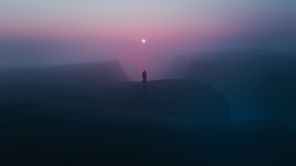 a person standing on top of a mountain at sunset