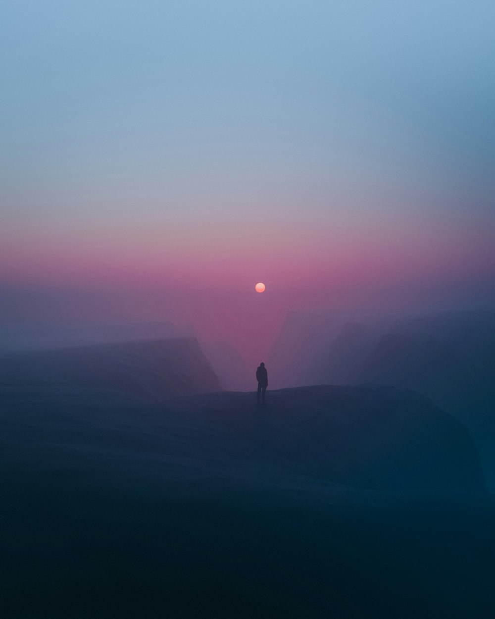 a person standing on top of a hill at sunset