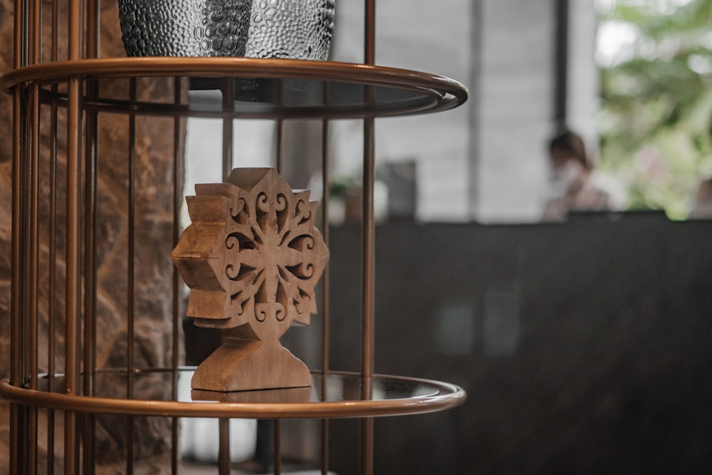 a birdcage with a wooden decoration on top of it