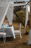 Elegant white chairs arranged around a beautifully set outdoor table under a modern canopy.