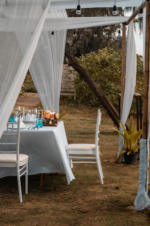 Elegant white chairs arranged around a beautifully set outdoor table under a modern canopy.