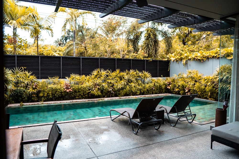 two lawn chairs sitting next to a swimming pool