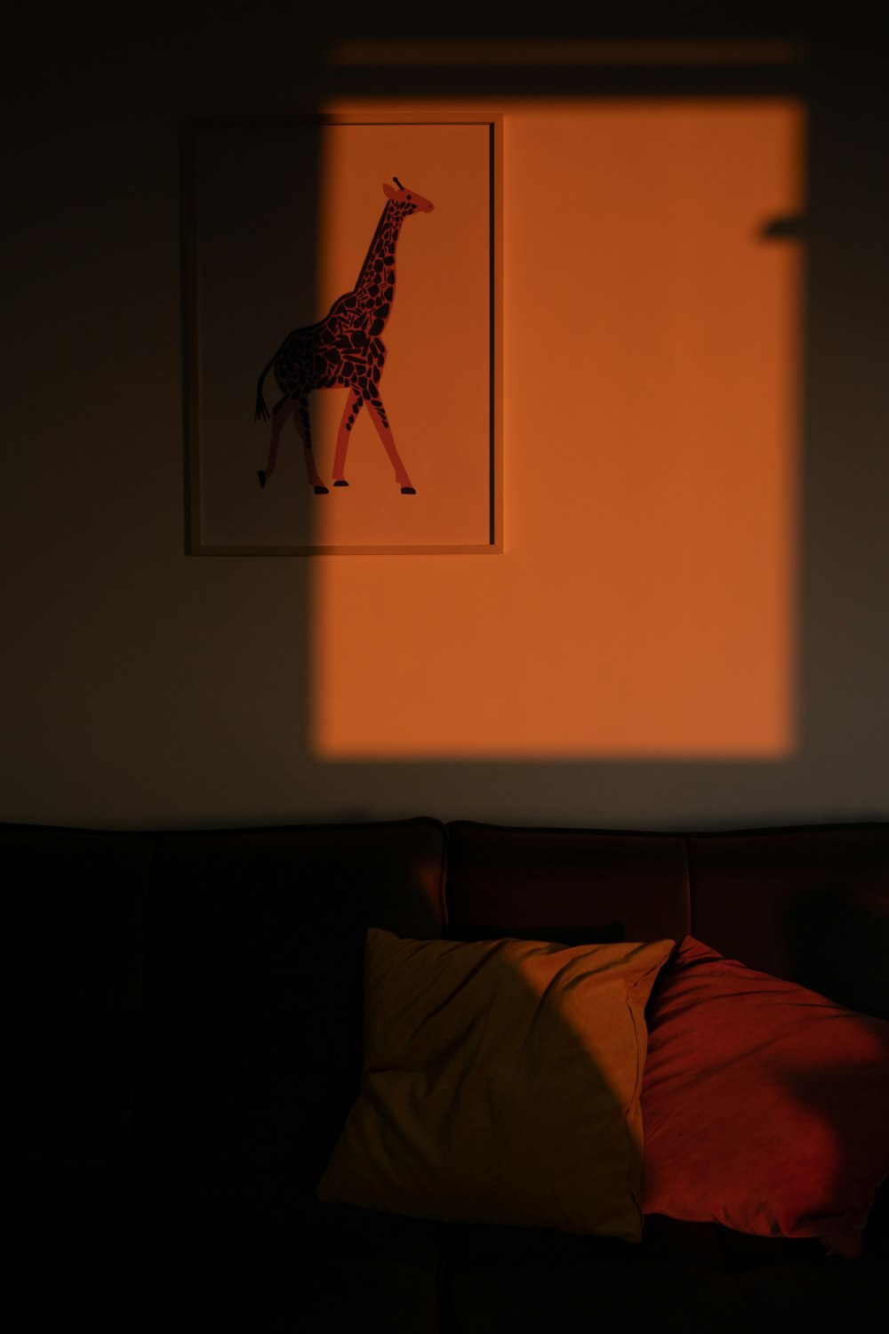 Una foto de una jirafa en una pared detrás de un sofá