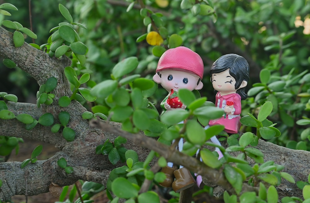 a couple of figurines sitting on top of a tree branch