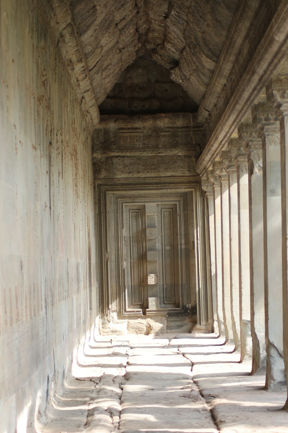 a long hallway in a stone building with columns