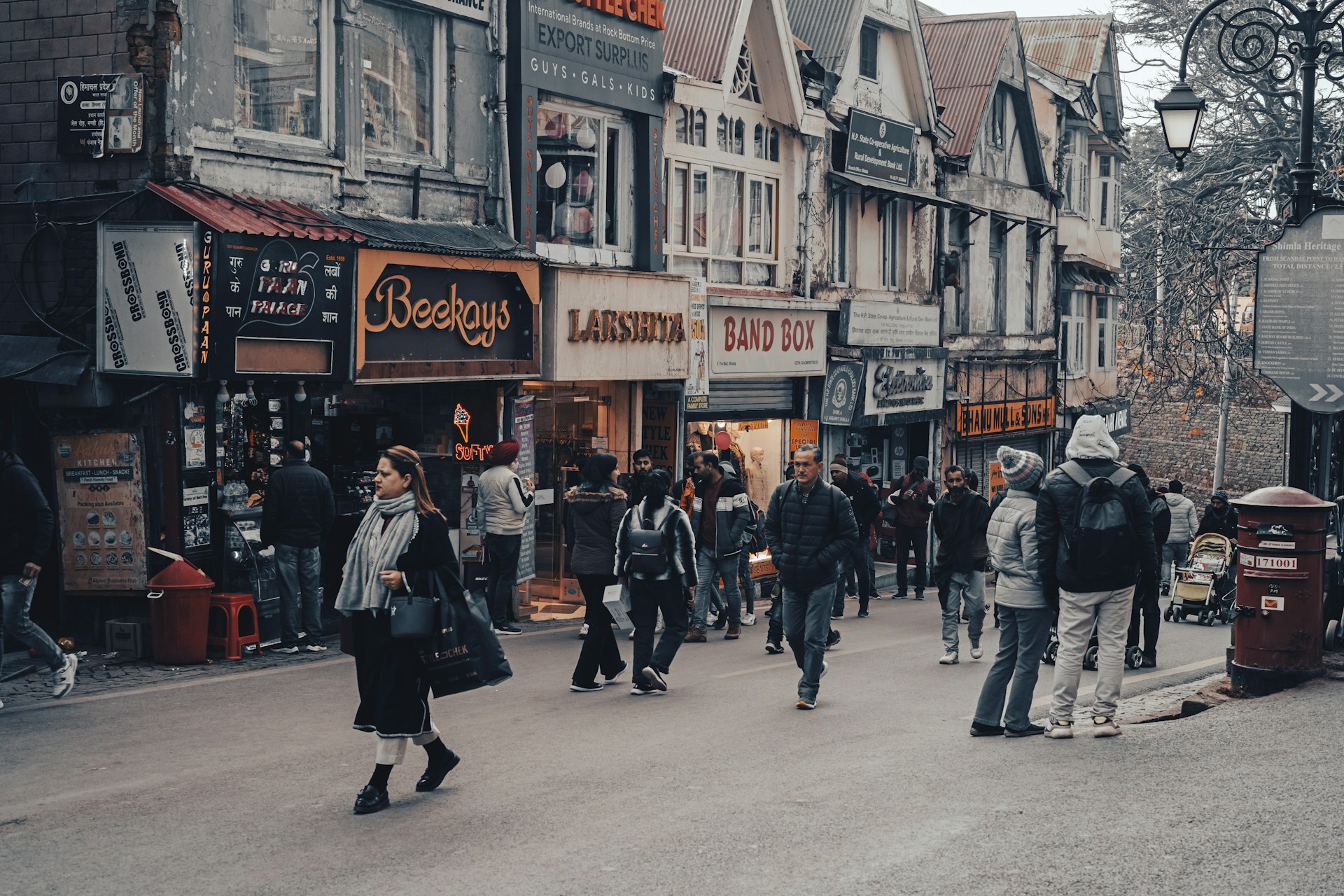 a group of people walking down a street next to tall buildings