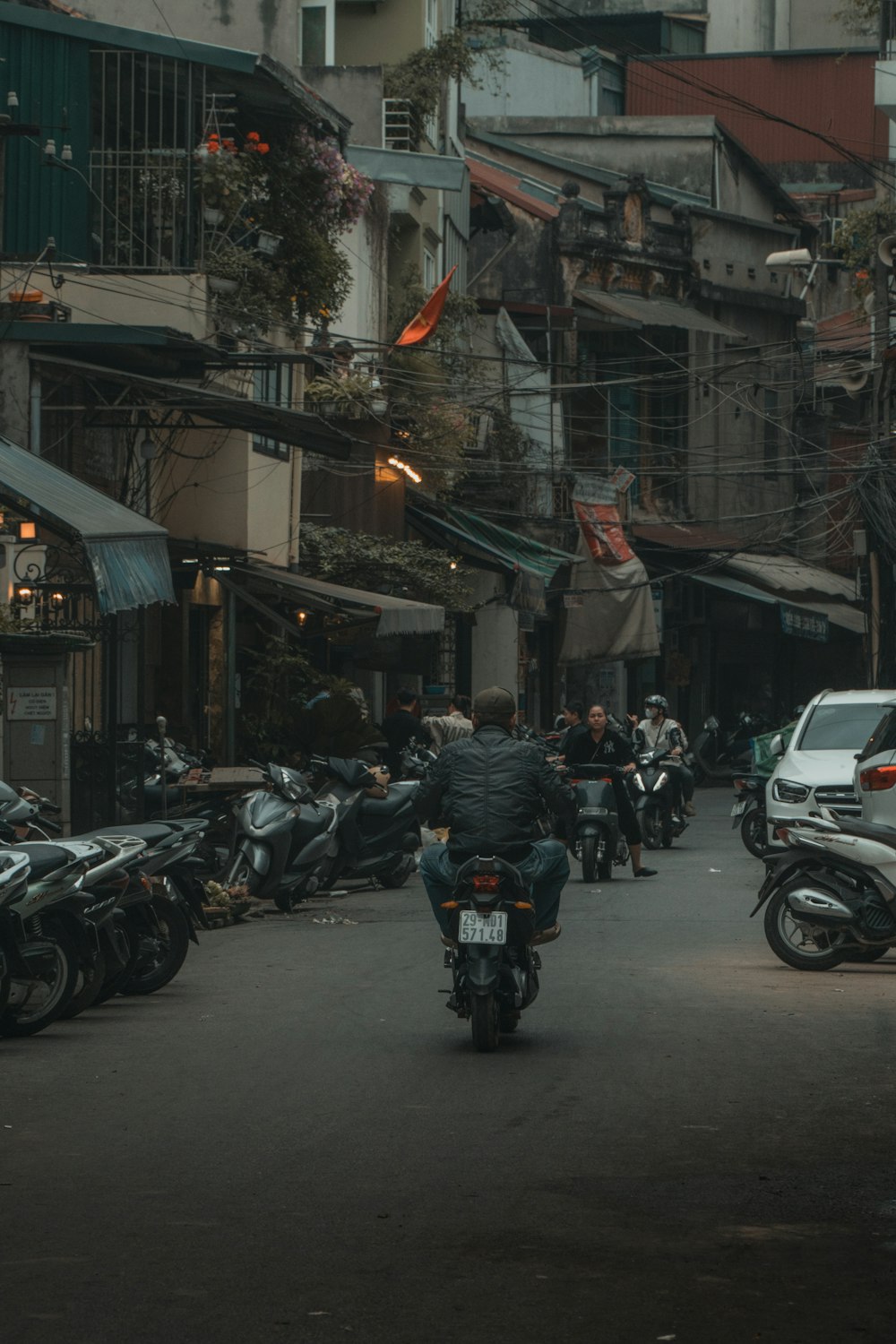 a man riding a motorcycle down a street next to parked motorcycles