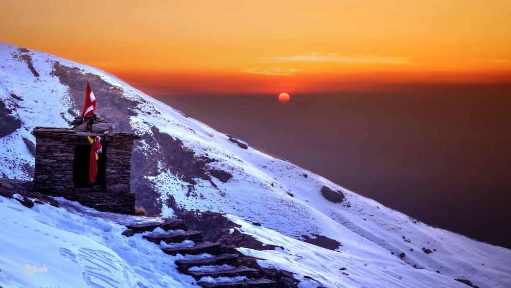 the sun is setting over a snowy mountain