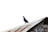 A pigeon is standing on a corrugated metal roof, which appears weathered and has rust stains. The background is a clear, bright sky.