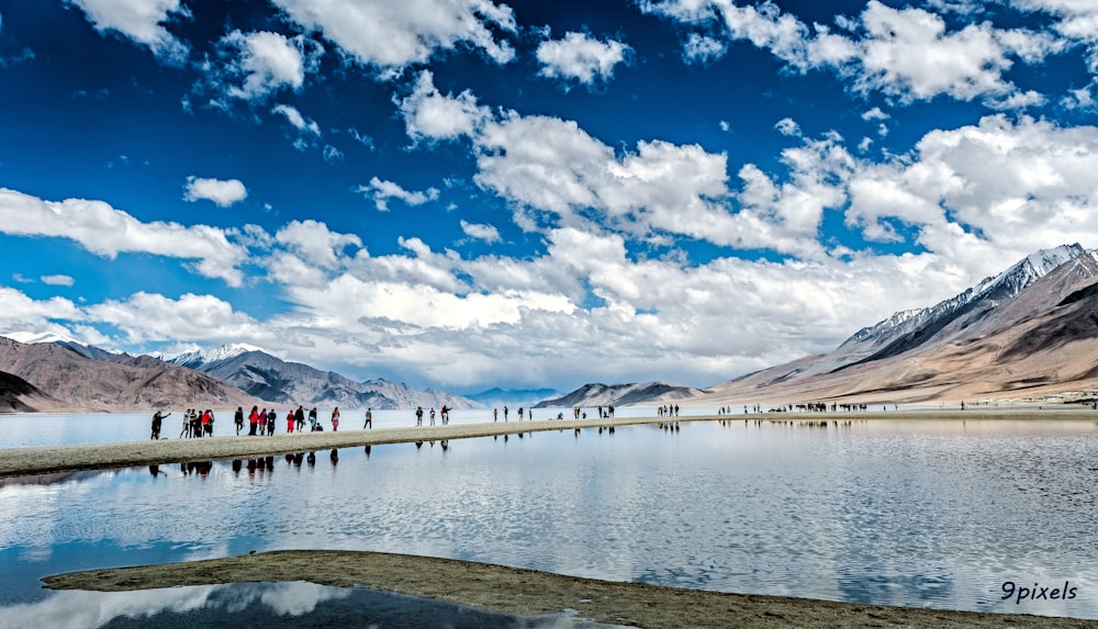 a group of people standing on the shore of a lake