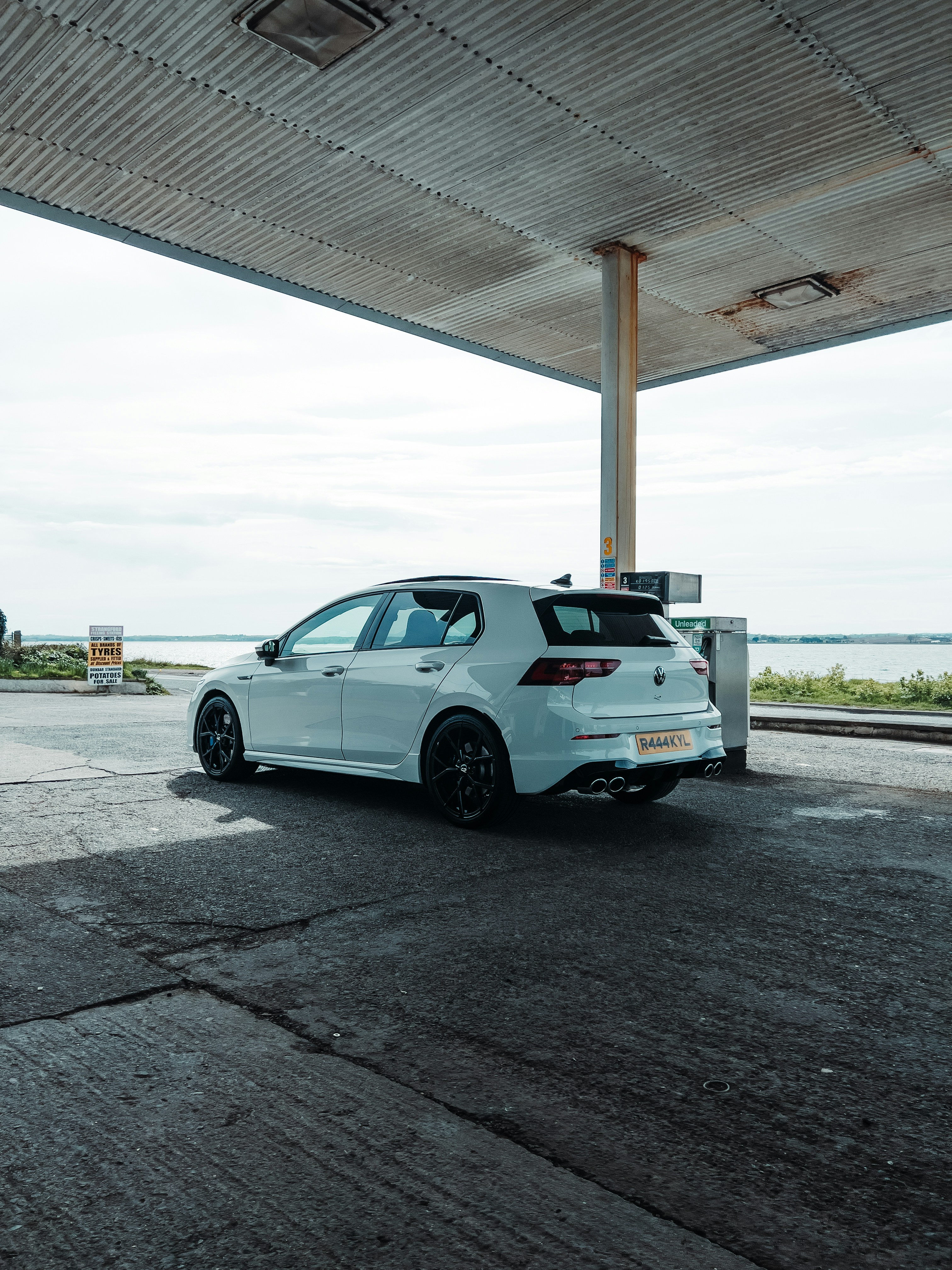a white car parked in a parking lot next to a gas station