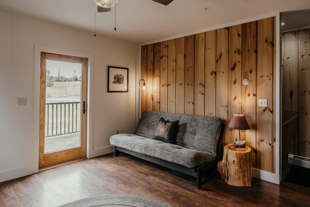 a couch sitting in a living room next to a wooden wall