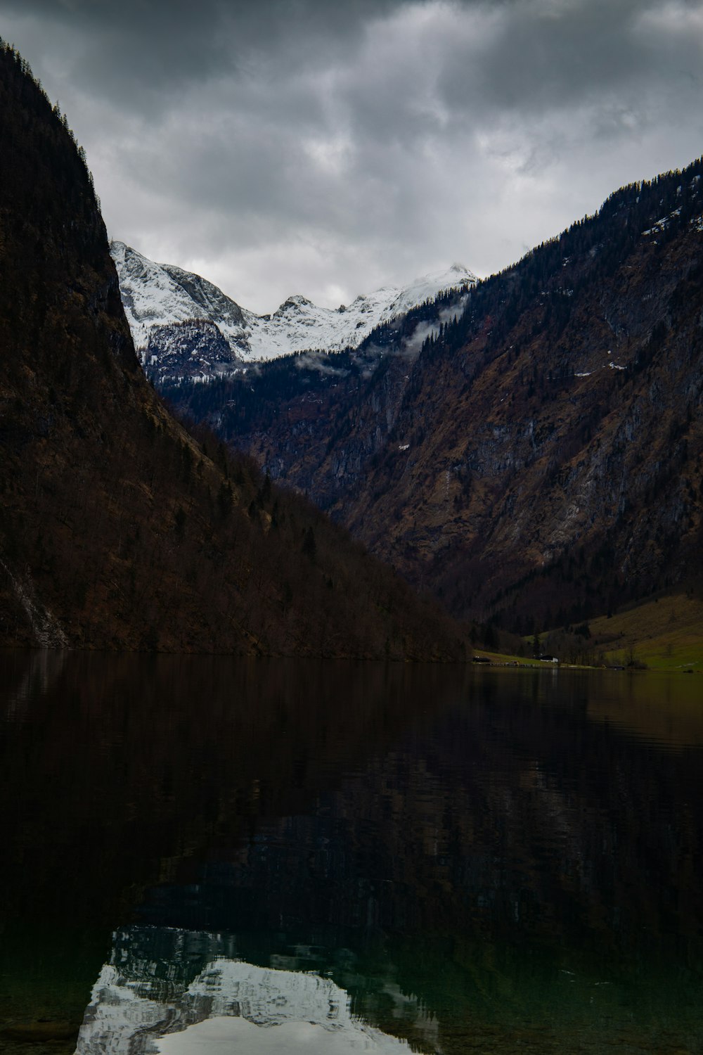 a body of water surrounded by mountains under a cloudy sky