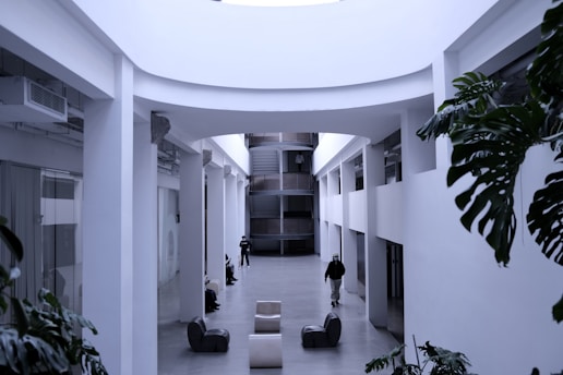 a man walking down a hallway between two buildings