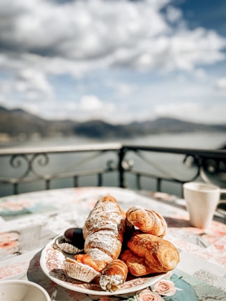 A charming café terrace overlooking a serene Swiss lake with pastries and coffee on the table.