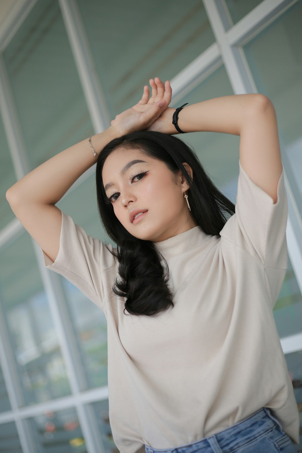 a woman with long black hair wearing a tan top